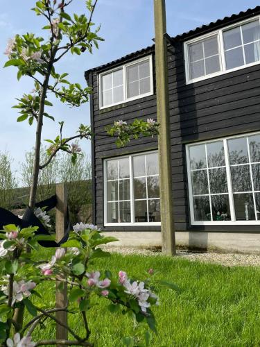 a black house with white windows at Blossom Barn Lodges in Oudewater