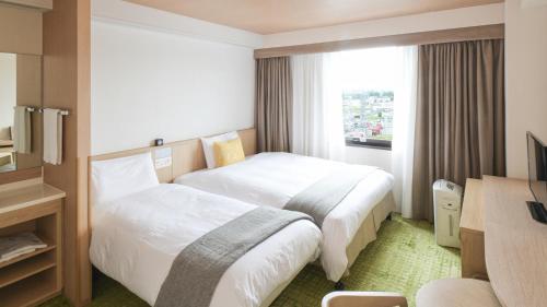 a hotel room with two beds and a window at Vessel Hotel Kumamoto Airport in Ozu