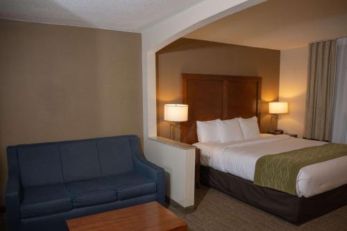a hotel room with a bed and a blue chair at Comfort Inn & Suites in Erie