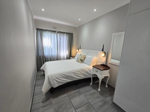 a bedroom with a bed and a table with a mirror at No8@Mosselbay - Central Mosselbay 1 Bedroom Apartment in Mossel Bay