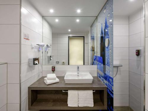 ein Bad mit einem Waschbecken und einem Spiegel in der Unterkunft ibis Styles Magdeburg in Magdeburg