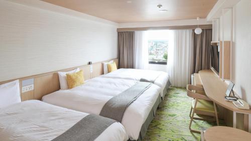 a hotel room with two beds and a desk at Vessel Hotel Kumamoto Airport in Ozu