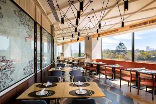 - un restaurant avec des tables, des chaises et de grandes fenêtres dans l'établissement Doubletree By Hilton Osaka Castle, à Osaka