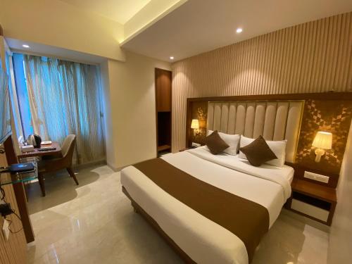 a hotel room with a large bed and a desk at Hotel Czar Inn - Vashi Navi Mumbai in Navi Mumbai