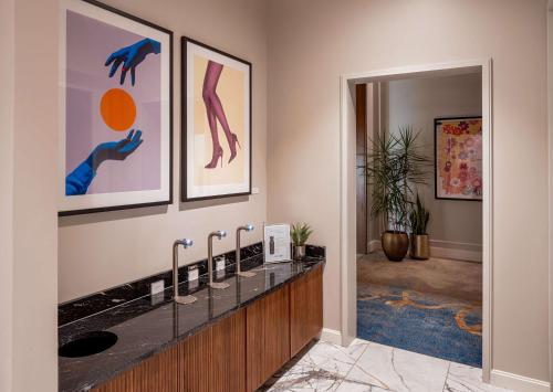 La salle de bains est pourvue d'un lavabo et de peintures murales. dans l'établissement Tempo By Hilton Nashville Downtown, à Nashville