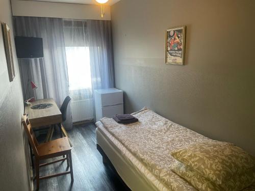 a bedroom with a bed and a desk and a window at Hostel Matkakoti Patria in Lahti