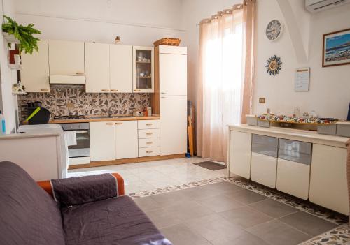 uma cozinha com armários brancos e um sofá em Ciuri Ciuri em Isola delle Femmine
