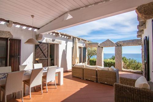 a patio with a table and chairs and the ocean at BGItalianVacation - Ville di Rocca Sant'Elmo in Castiadas