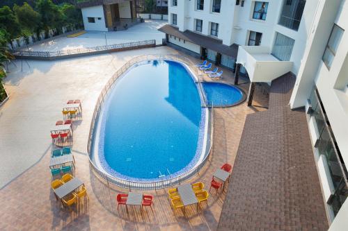 una vista sul tetto di una grande piscina con sedie e ombrelloni di AJ GRAND ELITE HOTEL a Mangalore