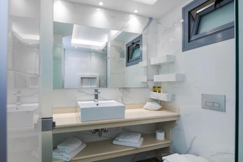 Agios Gordios Boutique Resort في آغيوس غوذيوس: حمام أبيض مع حوض ومرآة