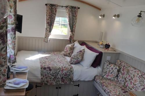 Shepherd Hut Enniskillen Blossom, Fermanagh في إنيسكيلين: غرفة نوم صغيرة مع سرير وأريكة
