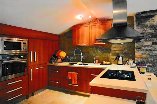 La cuisine est équipée de placards en bois et d'un four avec plaques de cuisson. dans l'établissement Тристаен апартамент -УЮТ и Топлина, à Yambol