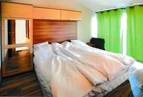 - un grand lit dans une chambre avec un rideau vert dans l'établissement Тристаен апартамент -УЮТ и Топлина, à Yambol