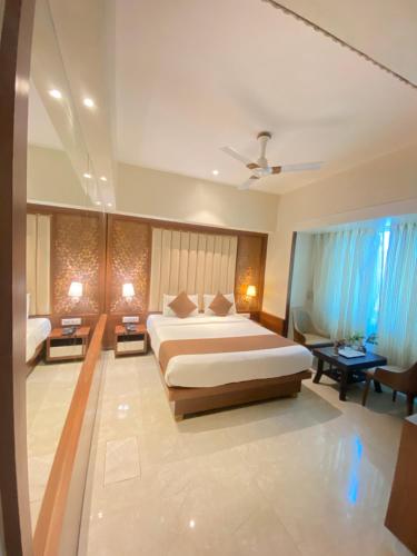 a large bedroom with a large bed and blue curtains at Hotel Czar Inn - Vashi Navi Mumbai in Navi Mumbai