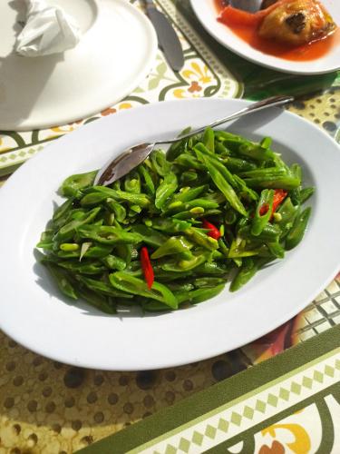 a plate of green beans with a spoon on a table at Tangkoko Jungle Homestay in Rinondoran