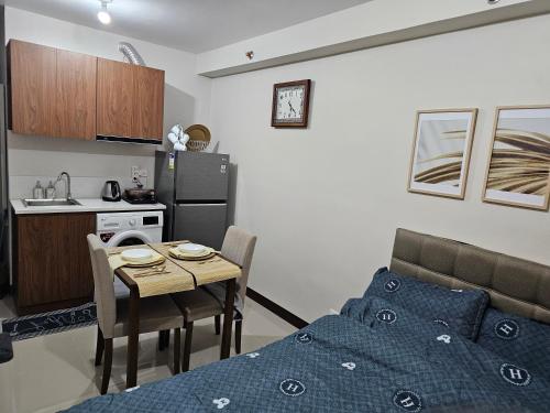 a room with a bed and a table and a kitchen at D' Kikays Saekyung Village 1 in Basbas