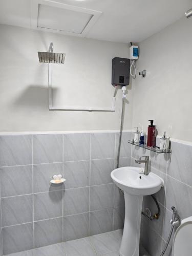 a white bathroom with a sink and a toilet at D' Kikays Saekyung Village 1 in Basbas