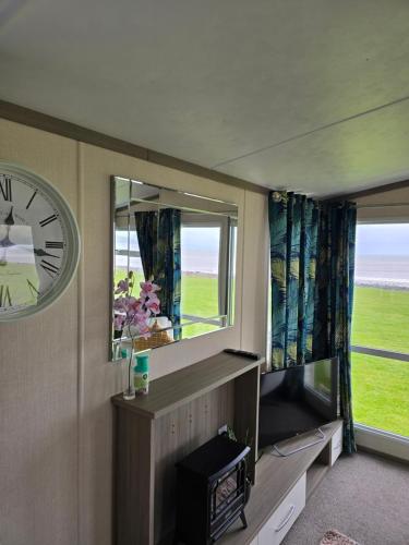 a room with a clock on the wall and a window at Bayview at Pengarreg in Llanrhystyd