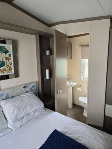 a bedroom with a bed and a bathroom with a sink at Bayview at Pengarreg in Llanrhystyd
