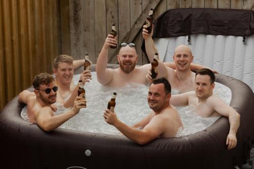 Eine Gruppe Männer in einem Whirlpool, die Bier halten. in der Unterkunft Cushendall Stables in Cushendall