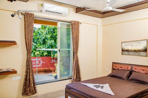 um quarto com uma cama e uma grande janela em Seasons The Resort em Alibag