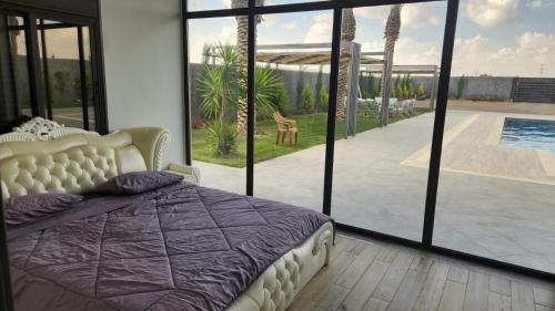 Schlafzimmer mit einem Bett und Poolblick in der Unterkunft ROSE in Umm el ‘Amad