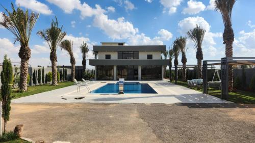 a house with a swimming pool and palm trees at ROSE in Umm el ‘Amad