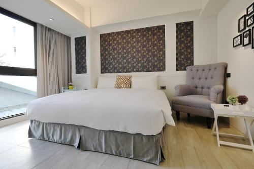 una camera con un grande letto e una sedia di 悅柏行旅 逢甲館 YABO Inn a Taichung