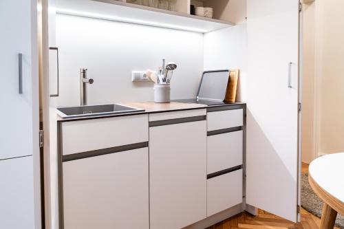 eine Küche mit weißen Schränken und einer Spüle in der Unterkunft twenty five - work & life Apartments in Amstetten