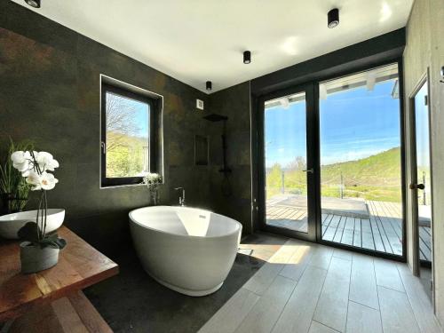 ein großes Bad mit einer Badewanne und einem großen Fenster in der Unterkunft KissHaz in Sovata