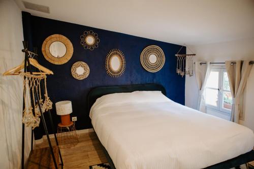 1 dormitorio con cama y pared azul con espejos en La maison du fermier, en Solliès-Pont