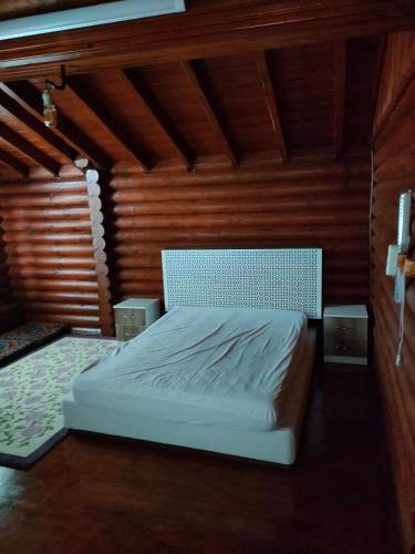 um quarto com uma cama branca numa parede de madeira em Chalet's lake_Bolu Abant _log house em Piroğlu