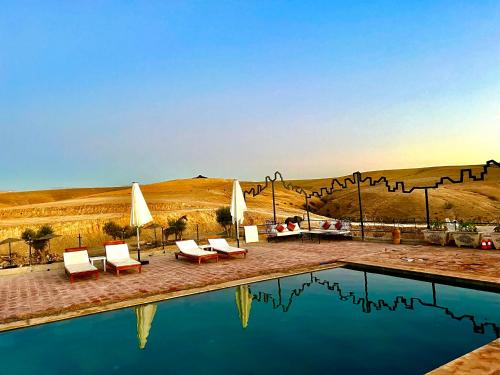 a pool with chairs and umbrellas next to a desert at AGAFAY BIV FOLK & SPA by WE CAMPS in Ourika