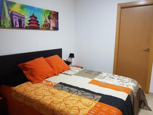 a bedroom with a bed with orange pillows and a painting at Apartamento marítimo Benicarló 2 dormitorios con aparcamiento in Benicarló