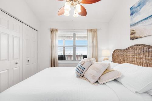 a white bedroom with a bed with a ceiling fan at Baywatch C10 in Pensacola Beach