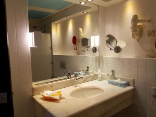 a bathroom with a sink and a large mirror at Kuwait Continental Hotel in Kuwait