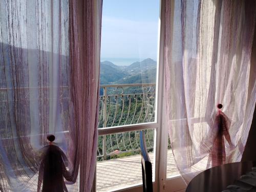 a window with curtains and a view of a mountain at Casa ivo in Perinaldo