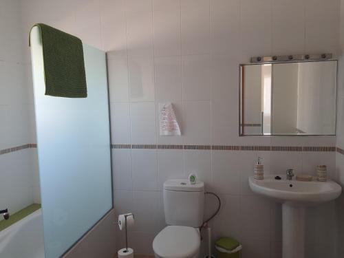 a white bathroom with a toilet and a sink at Villa Feliza in Güime