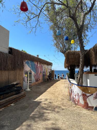 einen Bürgersteig neben einem Strand mit einem Baum und einem Gebäude in der Unterkunft Athena Tiny House in Bodrum City