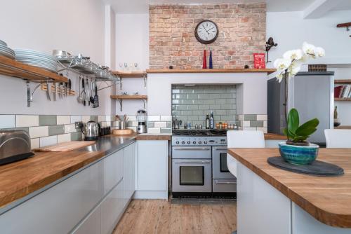a kitchen with white cabinets and a brick wall at Designer Maisonette Whole Apartment in Brighton & Hove