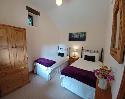 a bedroom with two beds and a dresser at River Cottage@Cwm Mill - Riverside Family Holidays in the Black Mountains in Hereford