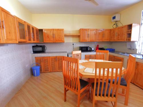 una cocina con armarios de madera, mesa y sillas en Sinthia Hotel Apartments, en Chaki Chaki