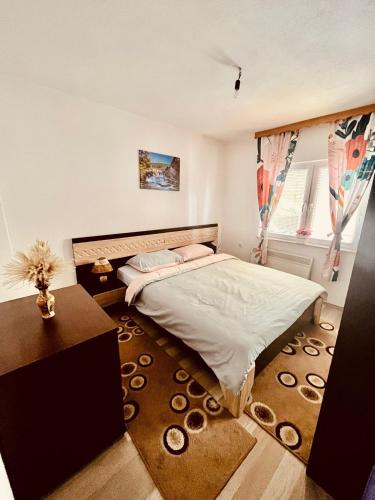 a bedroom with a bed and a table and a window at Summer house LejHana in Bihać
