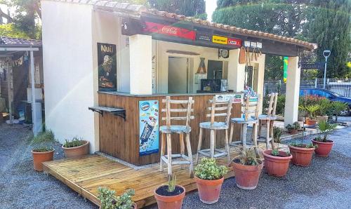 a bar with stools in front of a restaurant at Camping Porte des Alpilles by M.A DESTINATION GLAMPING in Saint-Étienne-du-Grès