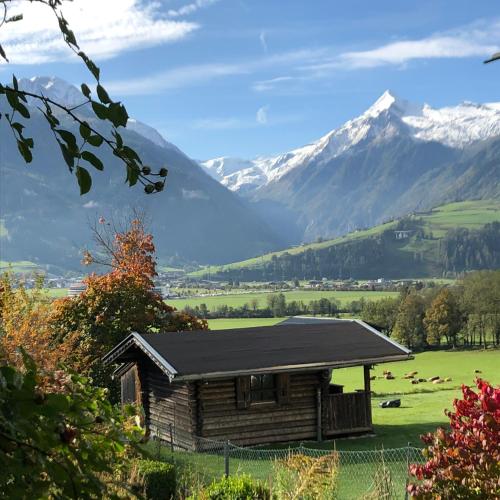 an old cabin in a field with mountains in the background at Haus Wenger Mountain View & Swimming Pool in Kaprun