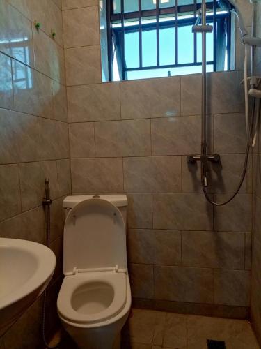 La salle de bains est pourvue de toilettes, d'un lavabo et d'une douche. dans l'établissement Kigali Grand Villa, à Kigali