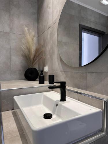 een badkamer met een witte wastafel en een spiegel bij Stegna Sea & Sun in Archangelos