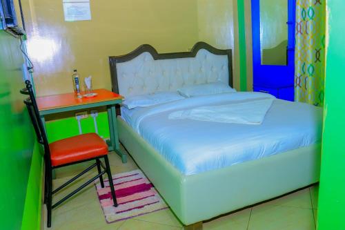 een slaapkamer met een bed, een tafel en een stoel bij Malibu Lounge Bar & Restaurant in Kisii