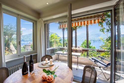 uma sala de jantar com mesa e cadeiras e janelas grandes em Queen Lake View - Happy Rentals em Ponte Tresa