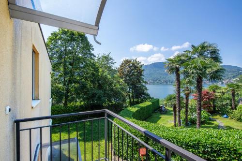 a balcony with a view of a lake and palm trees at Al Pontile Di Caslano - Happy Rentals in Caslano